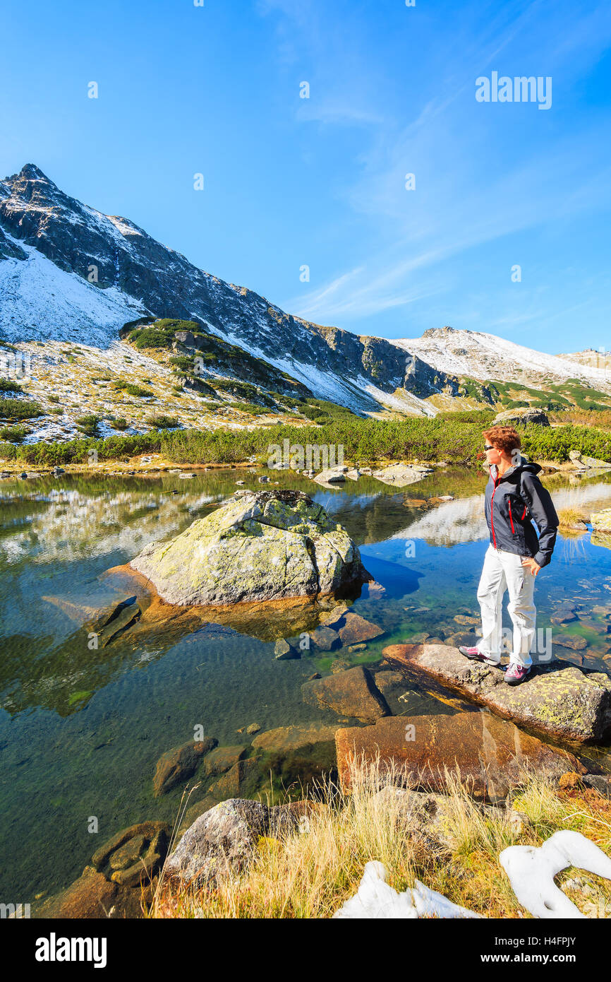 Young woman tourist standing on rock and looking at lake in autumn season, High Tatra Mountains, Poland Stock Photo