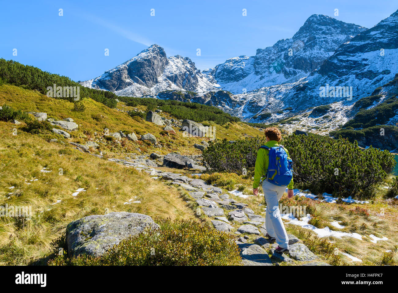 Young woman backpacker walking on mountain trail in Gasienicowa valley in autumn season, High Tatra Mountains, Poland Stock Photo