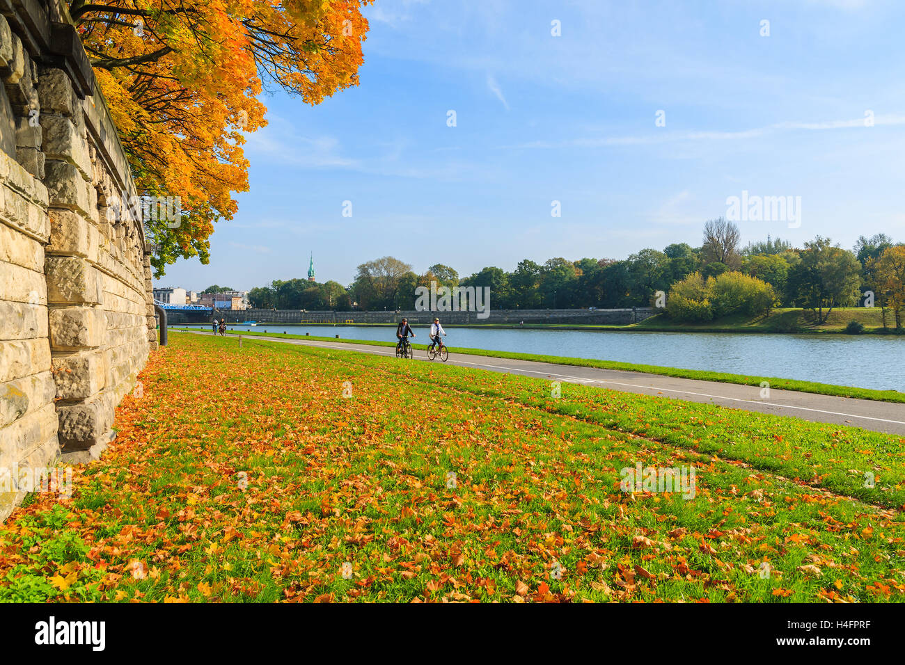 Couple of unidentified people riding bikes along a Vistula river in Krakow on sunny autumn day. Krakow is most visited city in Poland among foreign tourists. Stock Photo
