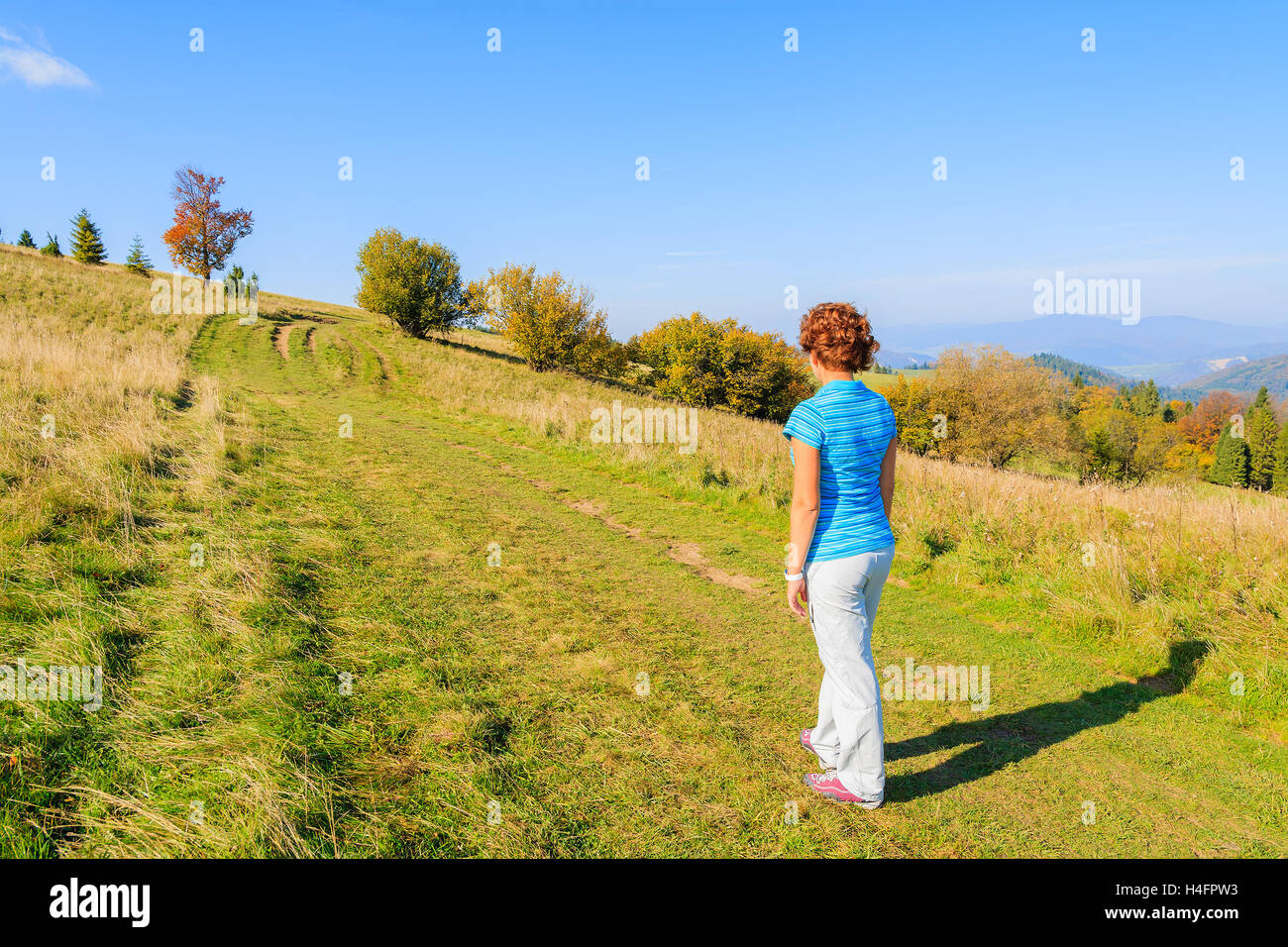 Young woman tourist standing on mountain path in Pieniny Mountains on sunny autumn day, Poland Stock Photo