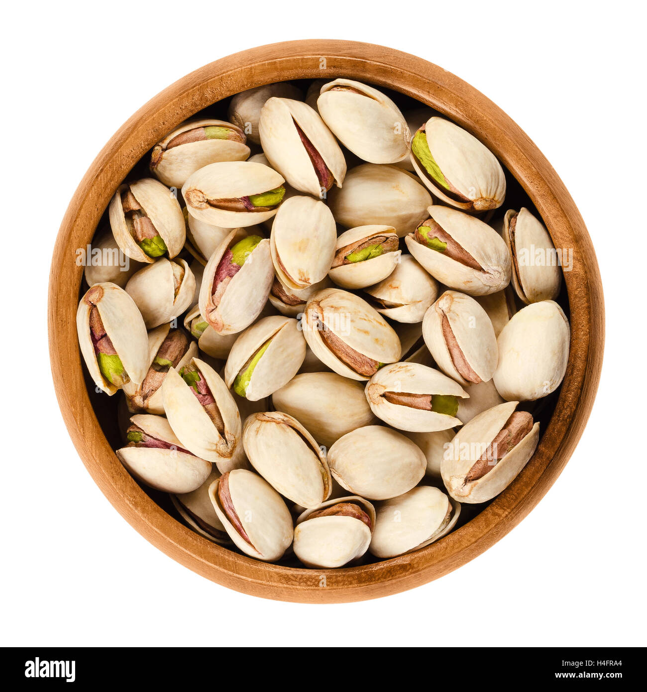 Roasted pistachio seeds with shell in wooden bowl on white background