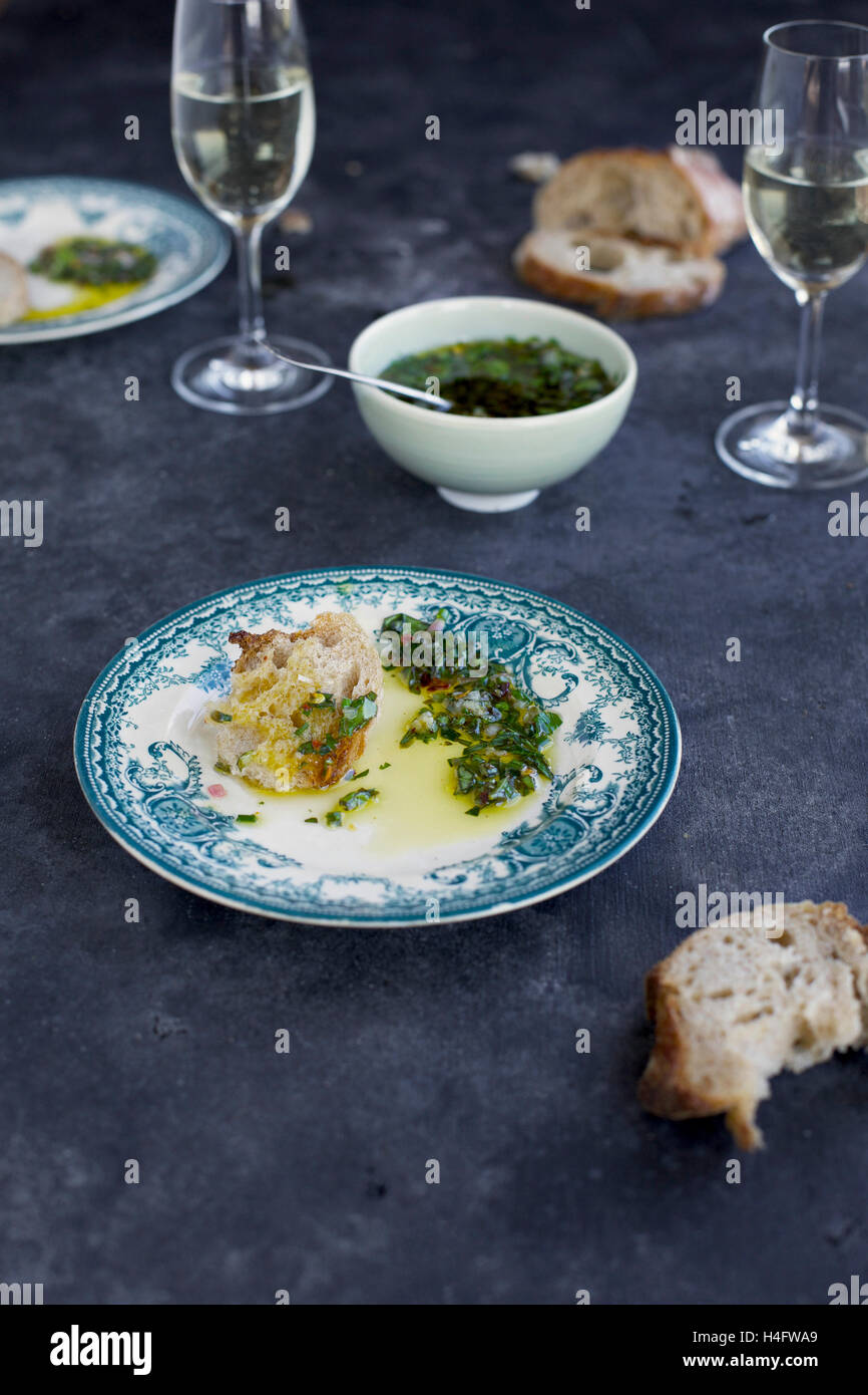 Italian Style Salsa Verde served with bread and white wine. Photographed from front view on a dark grey background. Stock Photo
