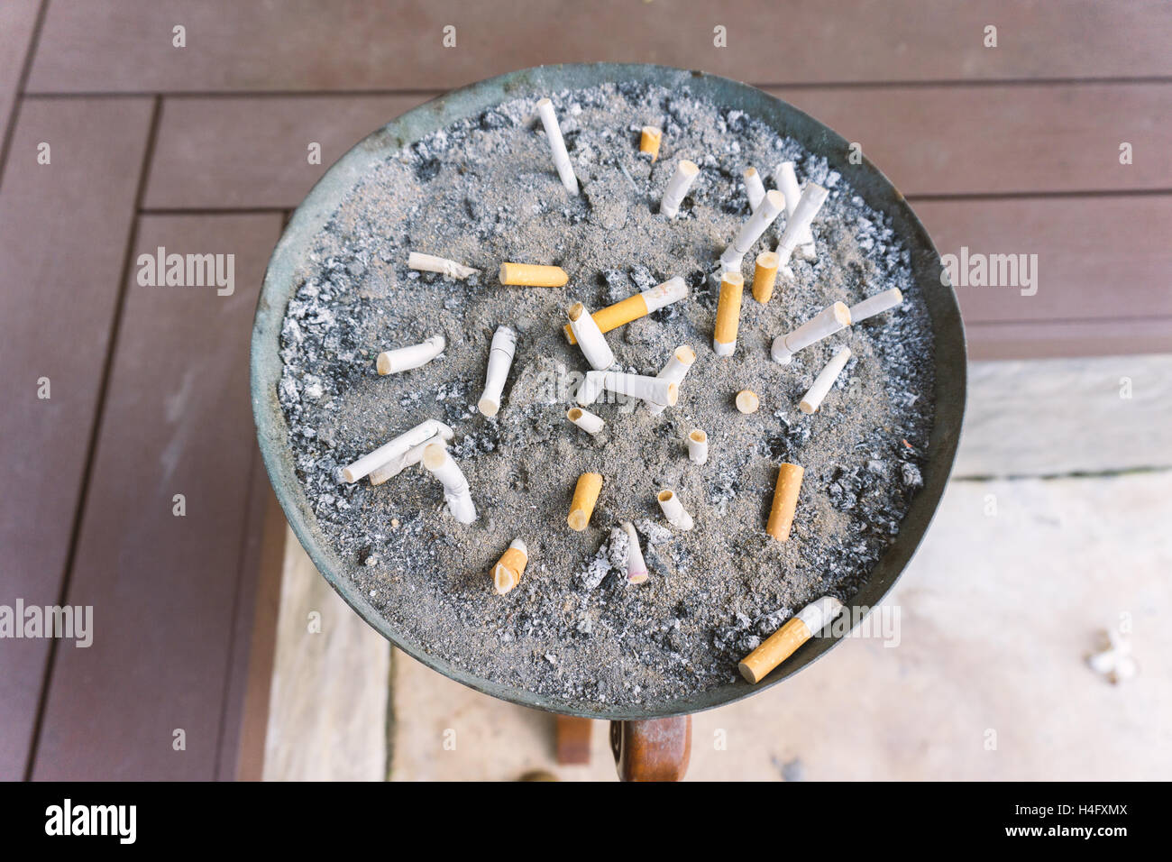 Cigarette in outdoors ashtray with sand closeup , process with vintage