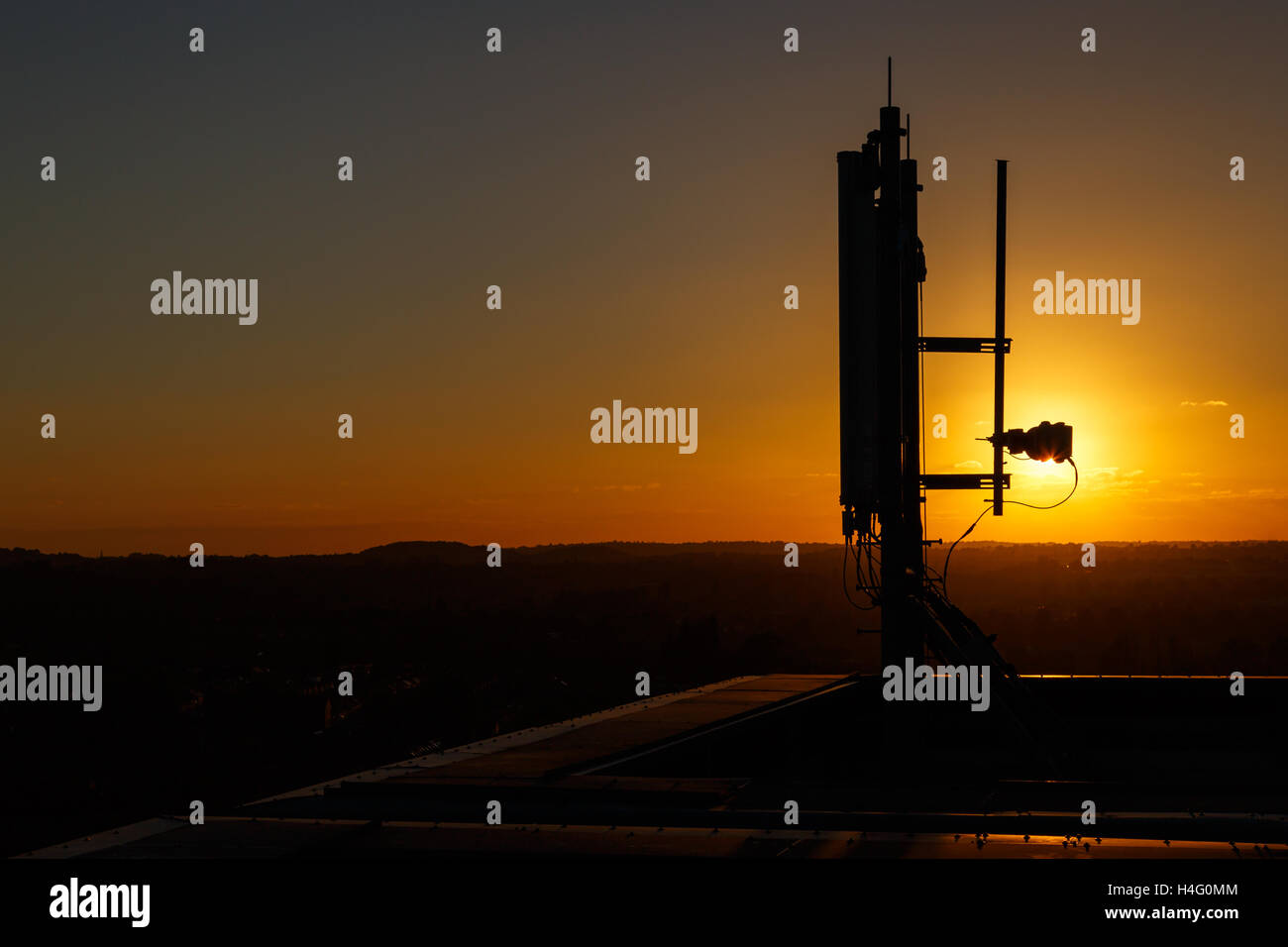 Mobile communications mast/antenna atop a tall building, against sunset. In Nottingham, England Stock Photo
