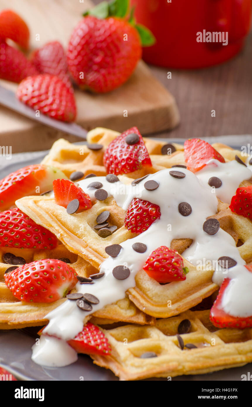 Homemade waffles with maple syrup and strawberries, topped cream and ...