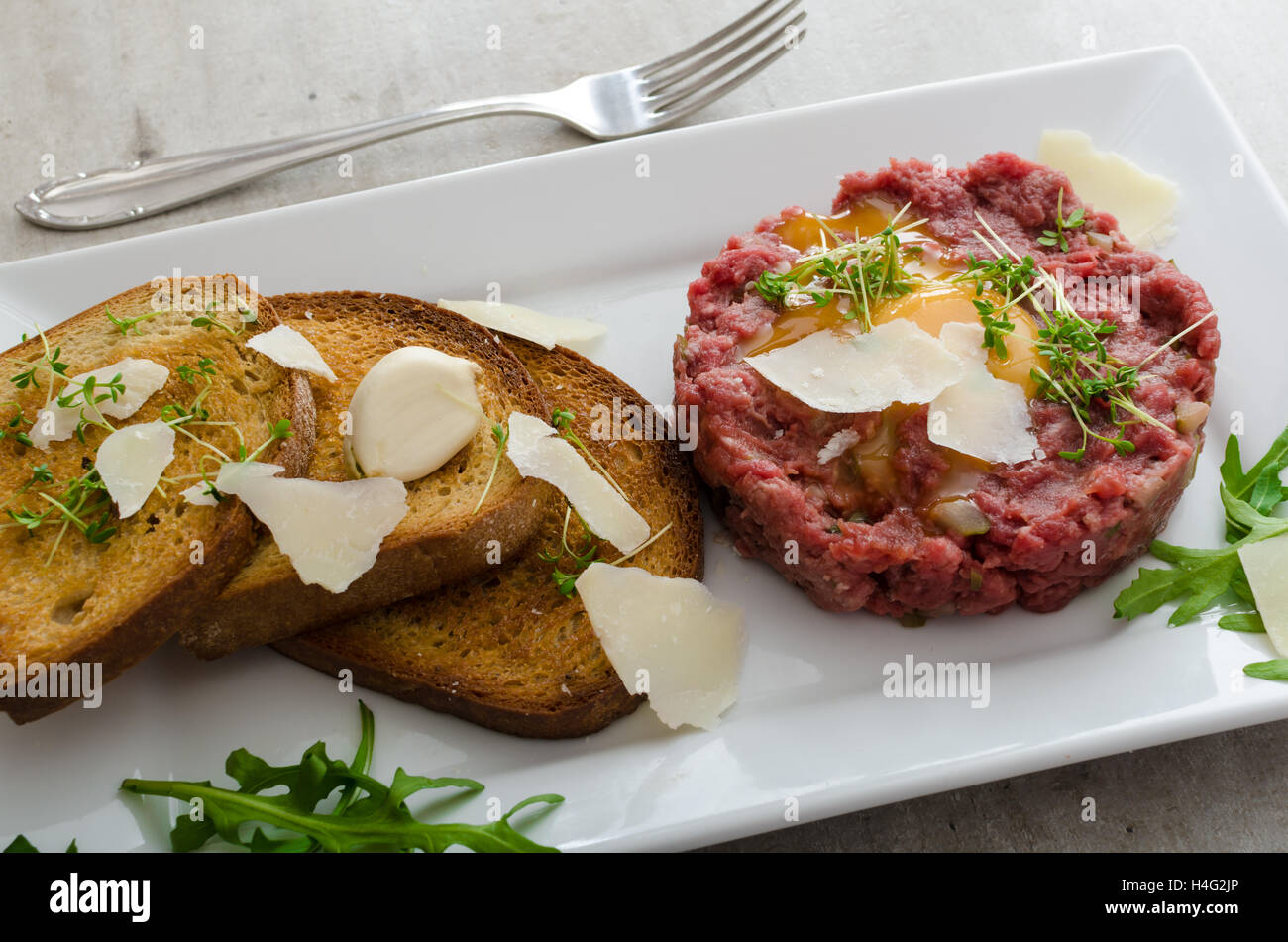 Beef tartar, toast bread with garlic, sprinkled with parmesan shavings