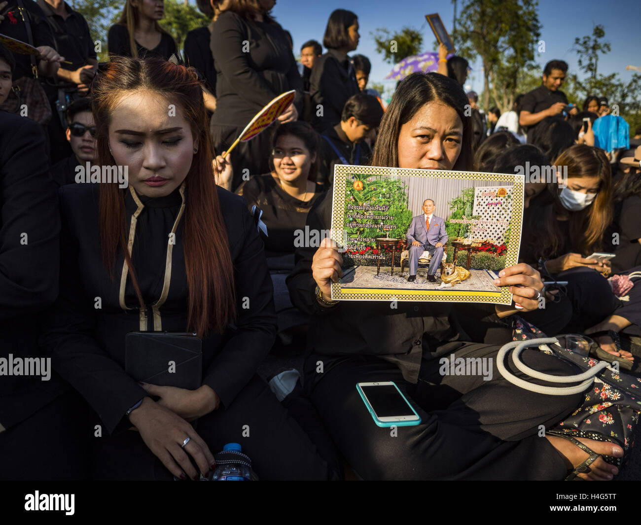 Bangkok, Bangkok, Thailand. 15th Oct, 2016. Women mourning the death of Bhumibol Adulyadej, the King of Thailand, sit on the sidewalk in front of the Grand Palace in Bangkok. King Bhumibol Adulyadej died Oct. 13, 2016. He was 88. His death comes after a period of failing health. With the king's death, the world's longest-reigning monarch is Queen Elizabeth II, who ascended to the British throne in 1952. Bhumibol Adulyadej, was born in Cambridge, MA, on 5 December 1927. He was the ninth monarch of Thailand from the Chakri Dynasty and is known as Rama IX. He became King on June 9, 1946 and s Stock Photo