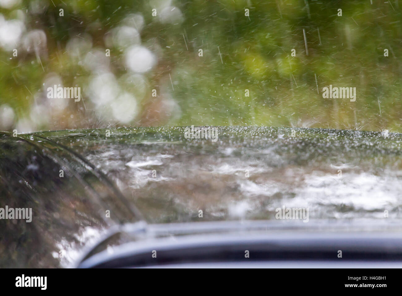 Heavy rain showers crossing the county. Car roof with heavy rain