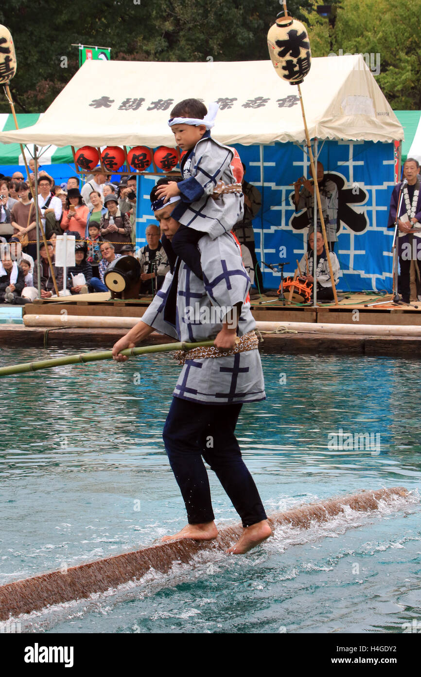 October 16, 2016, Tokyo, Japan - A raftsman, member of the Kiba 'kakunori' preservation society, carrying his son on his shoulders, performs a stunt on floating square timber logs at a festival in Tokyo on Sunday, October 16, 2016. The stunt was derived from lumberjacks daily work during the Edo period (1603-1868), when they made rafts with fire-hooks in their hands standing on floating logs.   (Photo by Yoshio Tsunoda/AFLO) LWX -ytd- Stock Photo