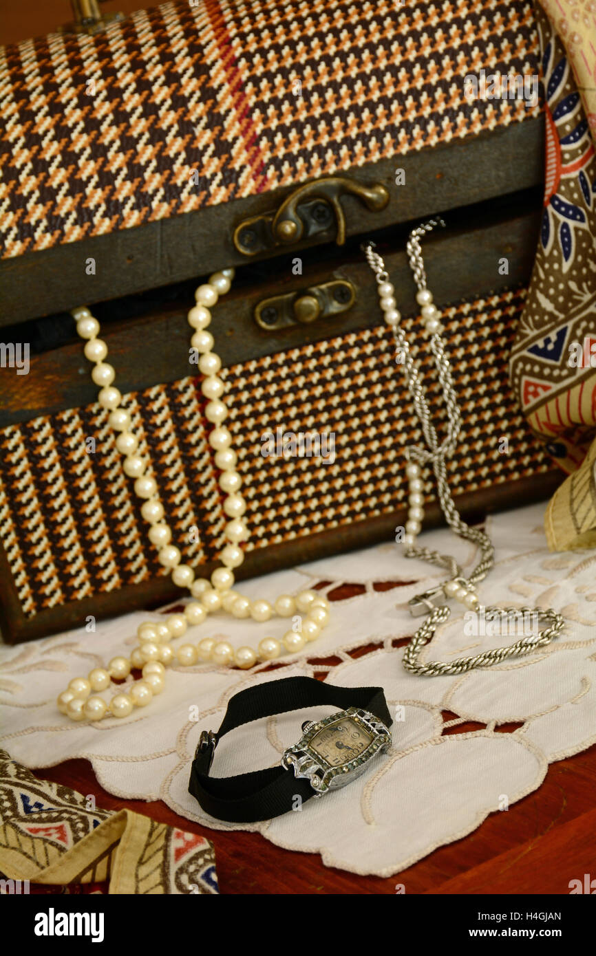 Still life of vintage jewellery in old fashioned plaid box.  Focus is on beautiful vintage watch in foreground. Stock Photo