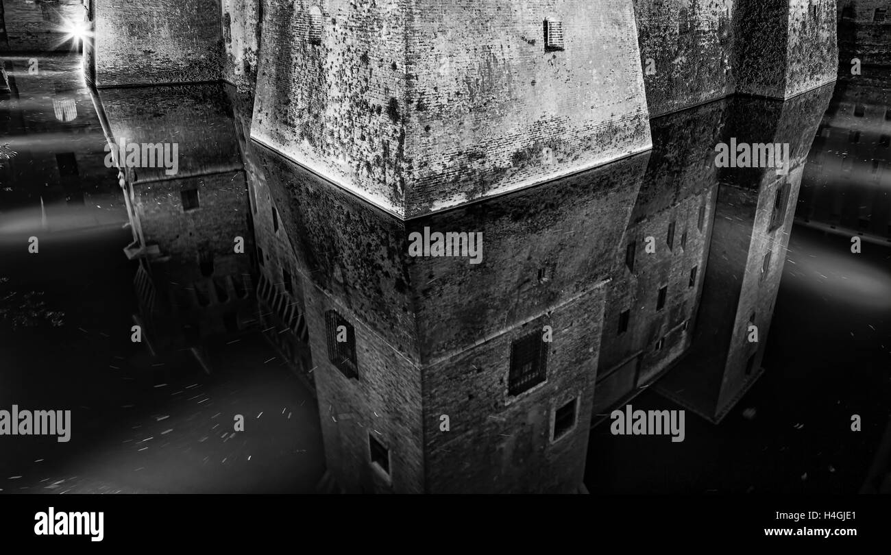 Corner fortification stone tower of ancient feudal castle in Mantua city of Italy. Water moat reflects powerful walls in black-w Stock Photo