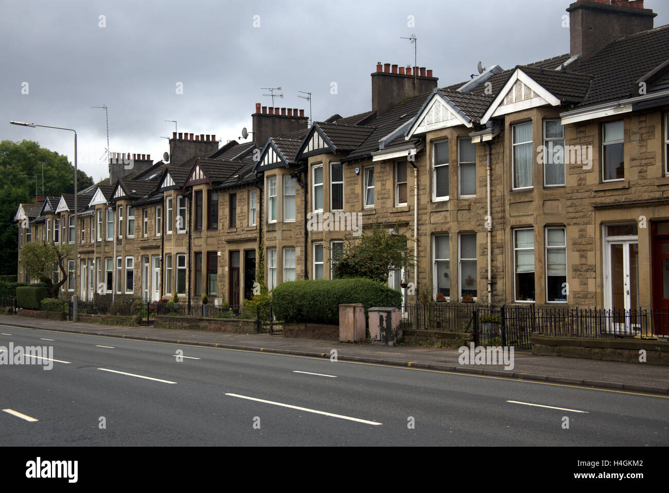 Line of Victorian blond sandstone terraced houses with no cars parked in front of them with an empty road Stock Photo