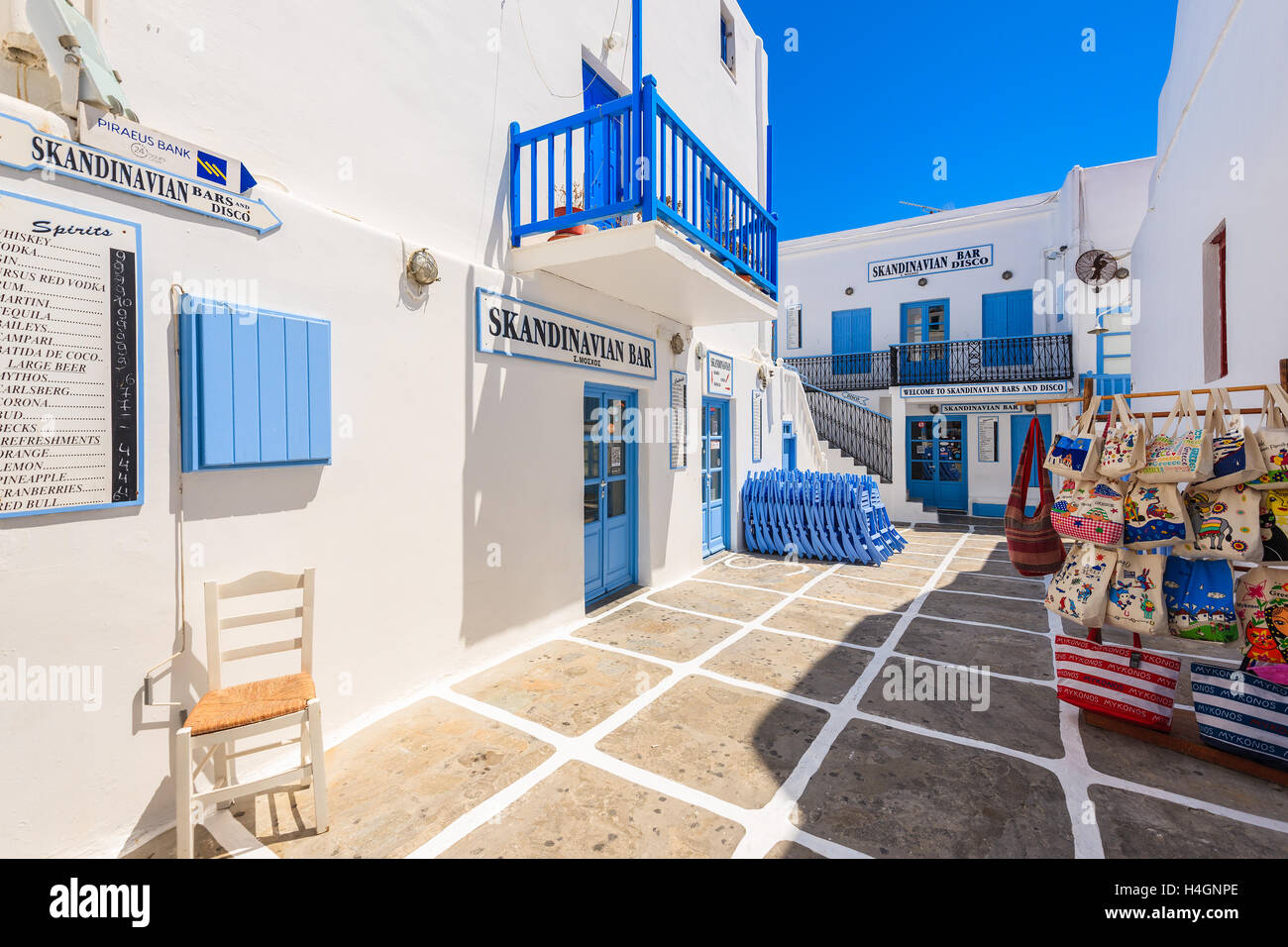 MYKONOS TOWN, GREECE - MAY 16, 2016: typical Greek bar and shop with tourist souvenir on street in Mykonos town, Greece. Stock Photo