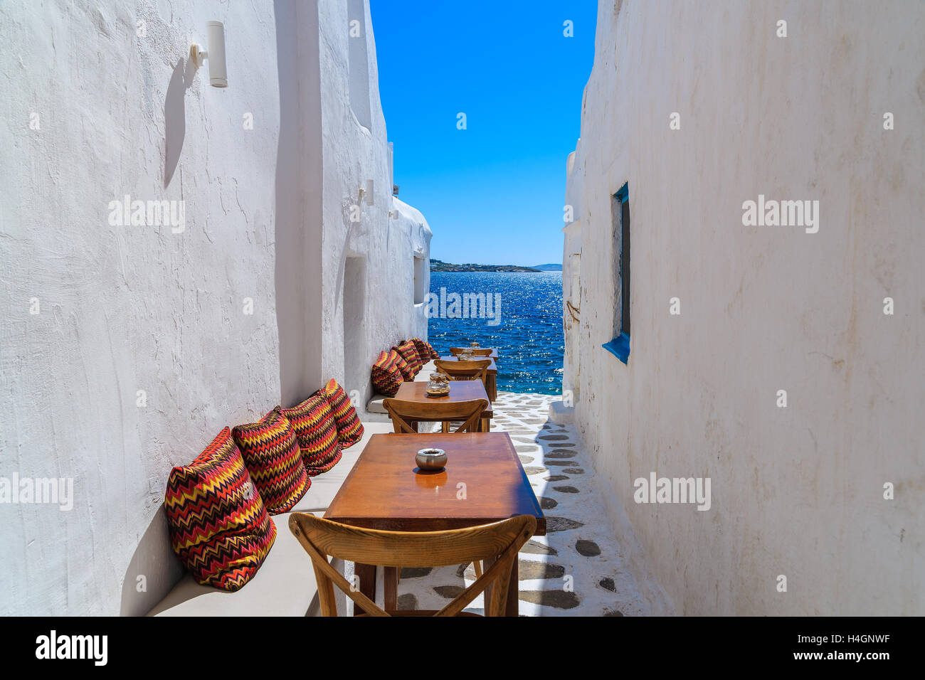 Benches with pillows in a typical Greek bar in Mykonos town with sea view, Cyclades islands, Greece Stock Photo