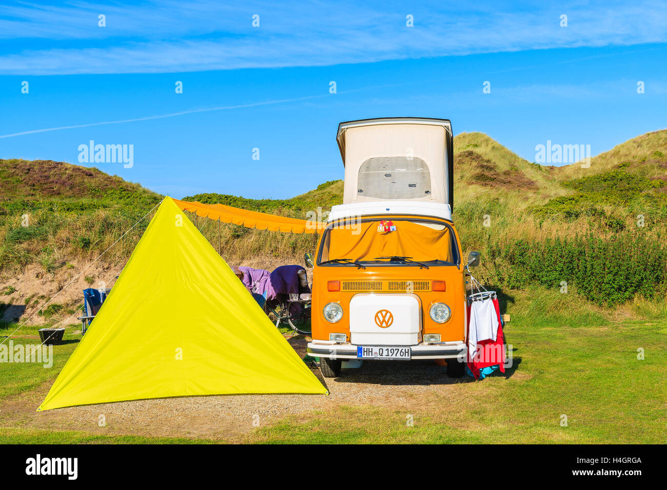 SYLT ISLAND, GERMANY - SEP 10, 2016: classic orange Volkswagen mini camper and yellow tent on green area of camping site located Stock Photo