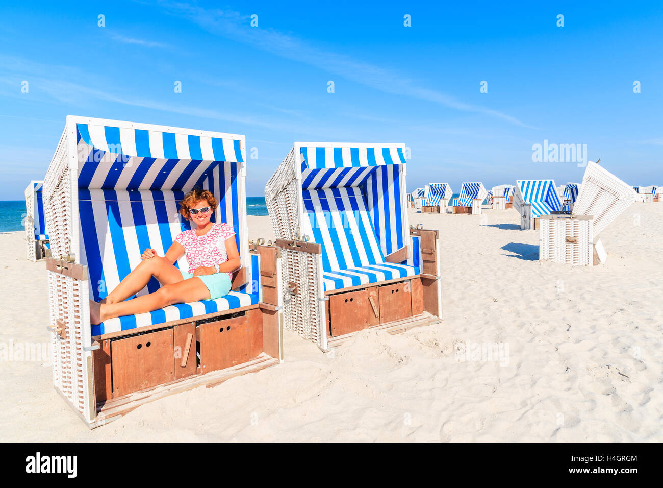 Happy woman sitting in beach chair and enjoying summer time, Kampen, Sylt island, Germany Stock Photo