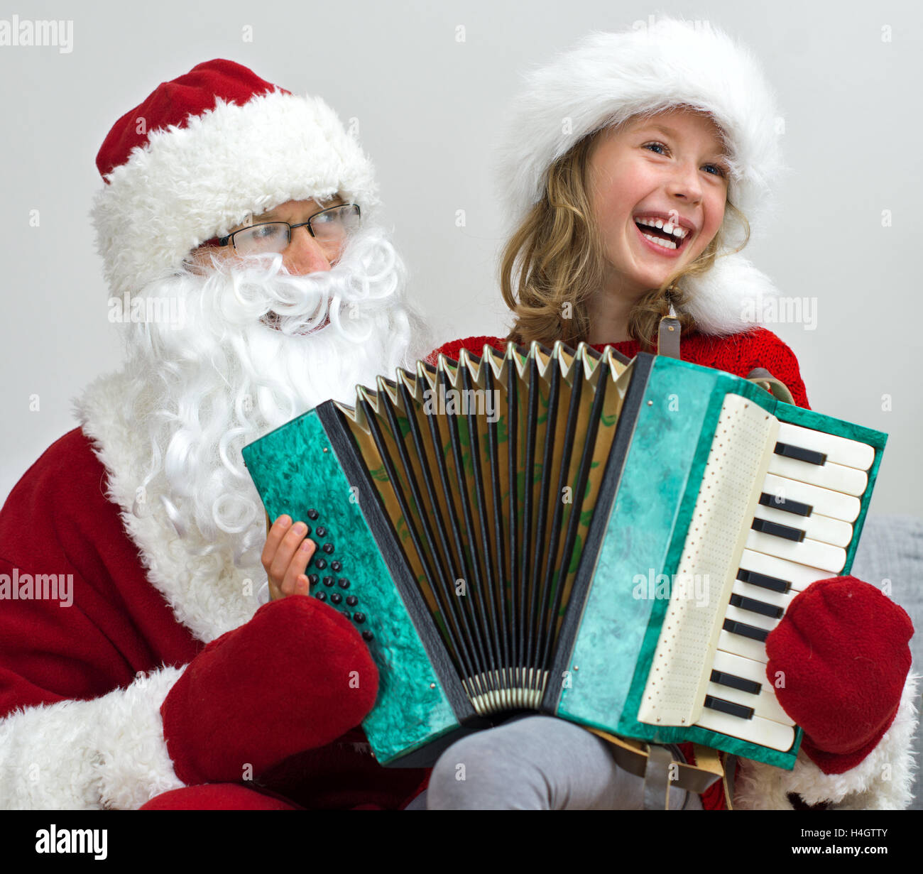 Santa Claus and little girl playing accordion at Christmas. Stock Photo