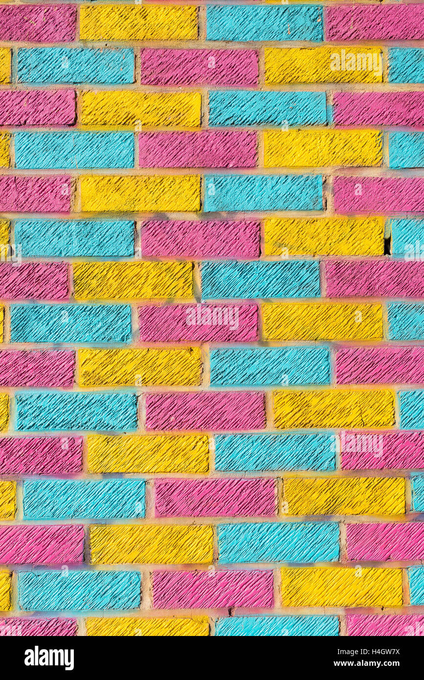 Brick wall painted in bright yellow, blue and pink colors Stock Photo