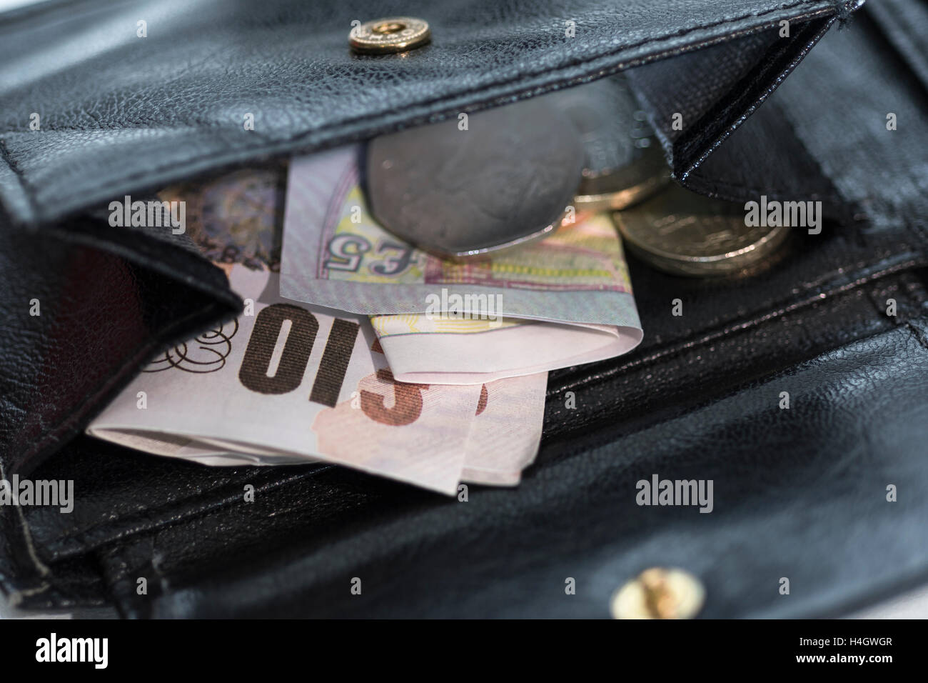 Picture of open purse/wallet revealing loose change & money - metaphor for 'rising cost of living' , affordability, shop prices, low income concept. Stock Photo