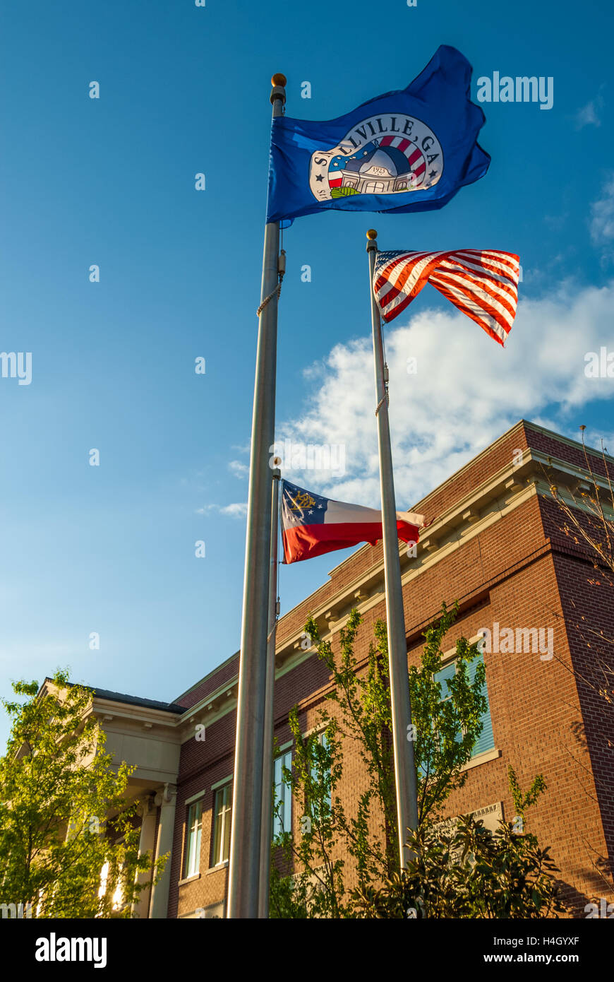 US, Georgia, and Snellville city flags unfurled in the wind at sunset in front of the City Hall building in Snellville, Georgia. Stock Photo