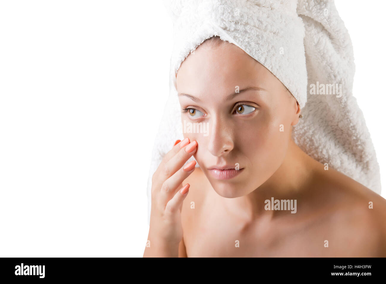 Woman with a towel wrapped around her head checking her skin, isolated in white Stock Photo