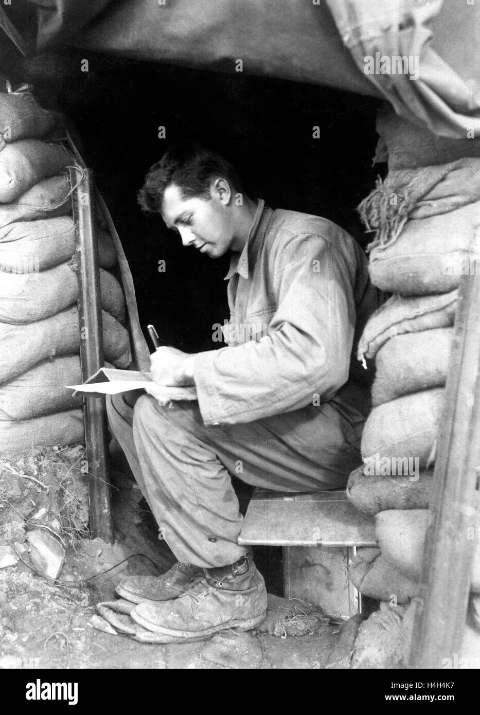 U.S. soldier Pfc. Dwight Exe, with the 5th Cavalry Regiment, writes a letter home during a break in fighting along the front with North Korea during the Korean War November 15, 1951 in Korea. Stock Photo