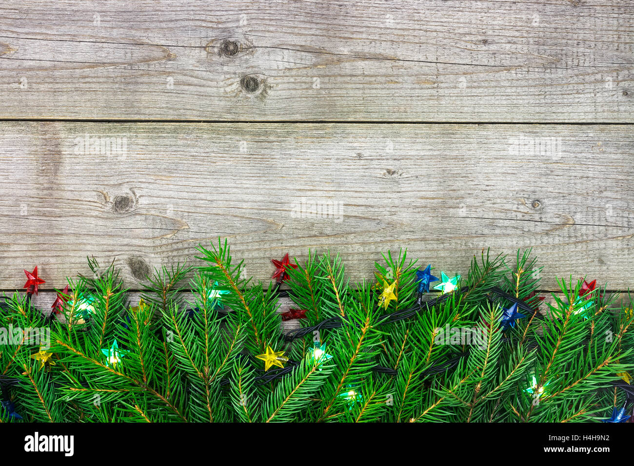Christmas fir tree branch decorated with garlands of lights on wooden ...