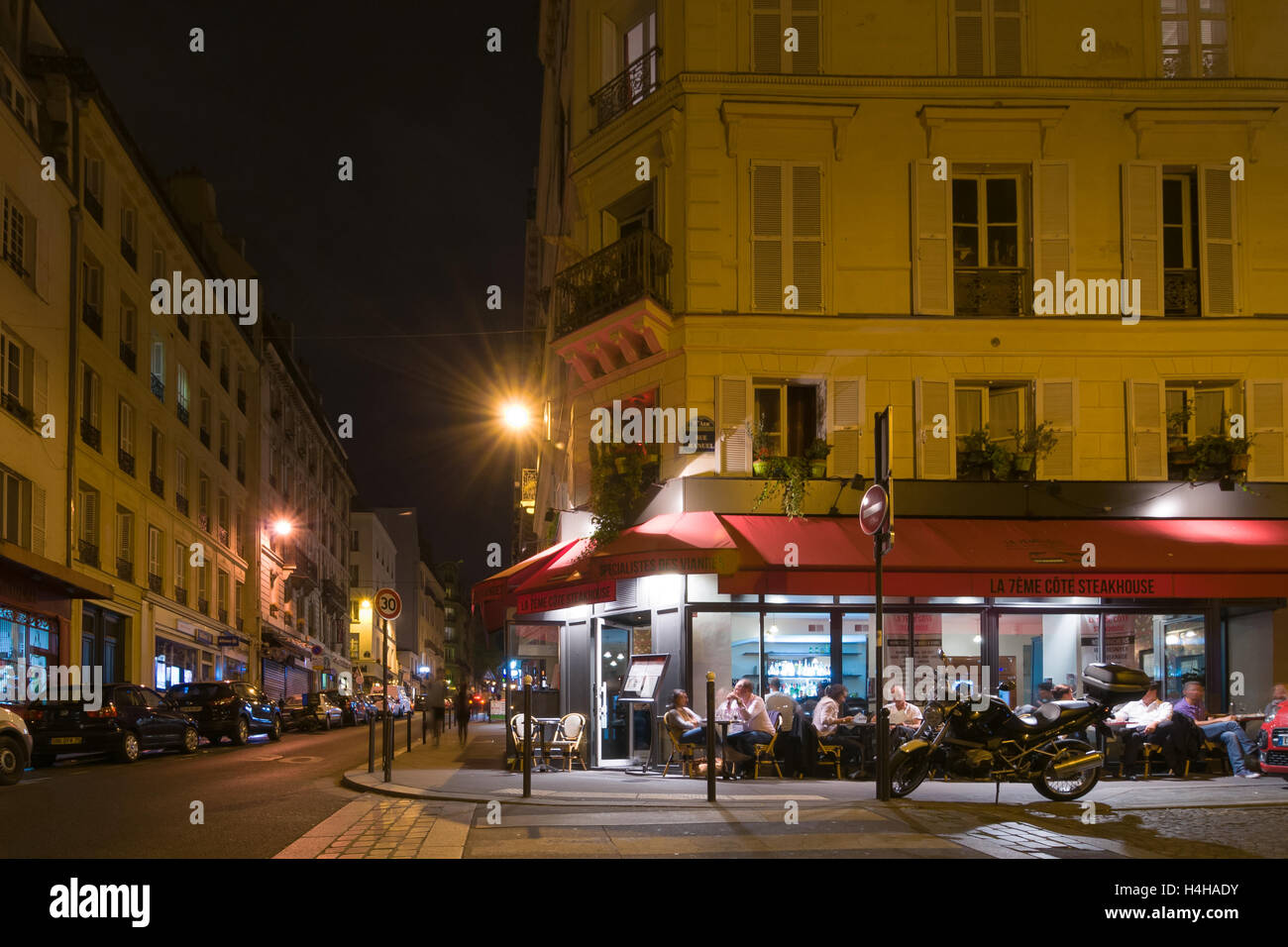 PARIS - SEPT 17, 2014: Paris by night. The people sit and talk in a cafe. Paris, France. Stock Photo