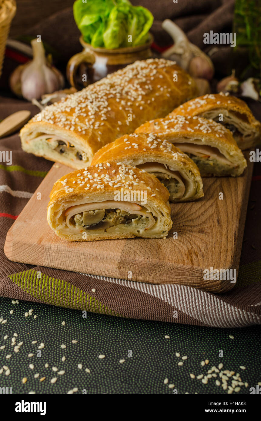 Roll out puff pastry stuffed with mushrooms, cheese and ham Stock Photo