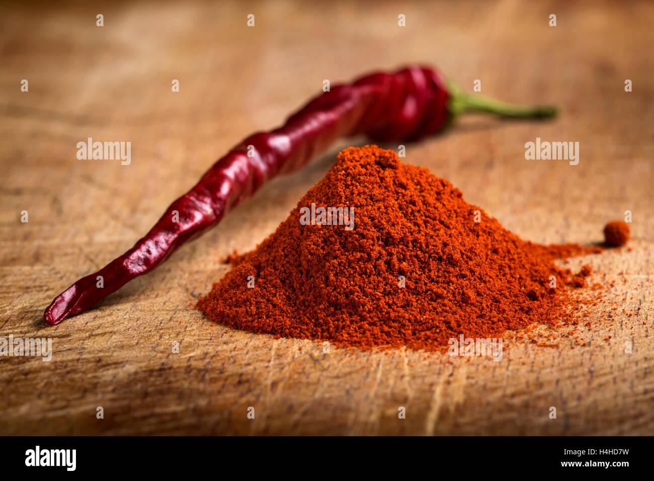 Red hot paprika powder heap and one dried chilli on wooden background Stock Photo Alamy