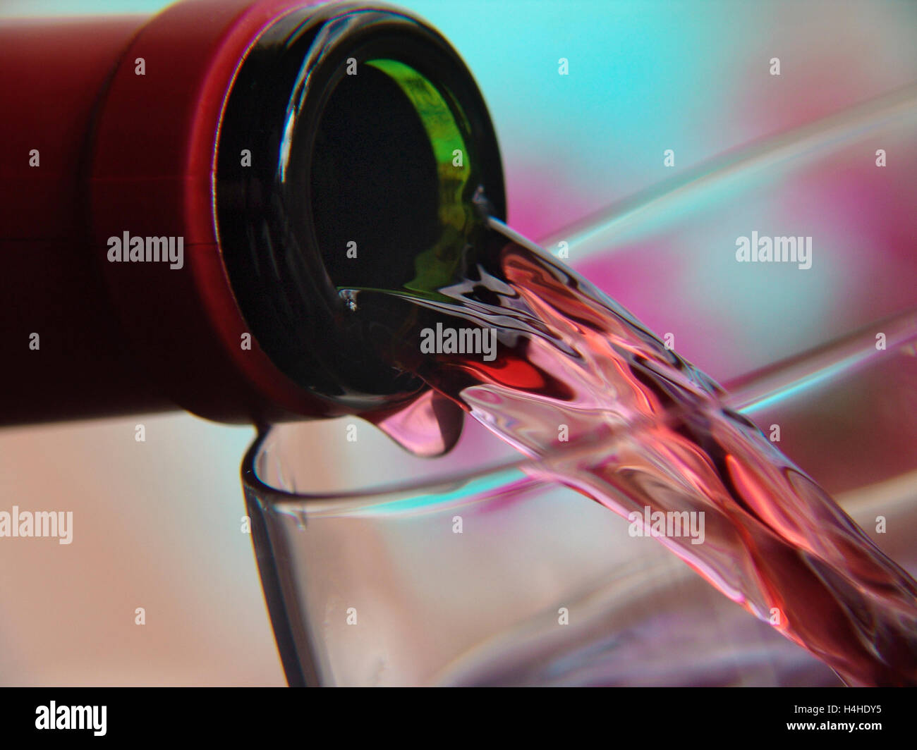 Pouring rose wine into a wine glass with garden flowers in background ...