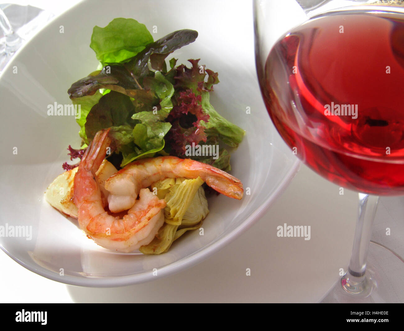 Glass of rosé wine with seafood salad on alfresco sunlit restaurant table Stock Photo