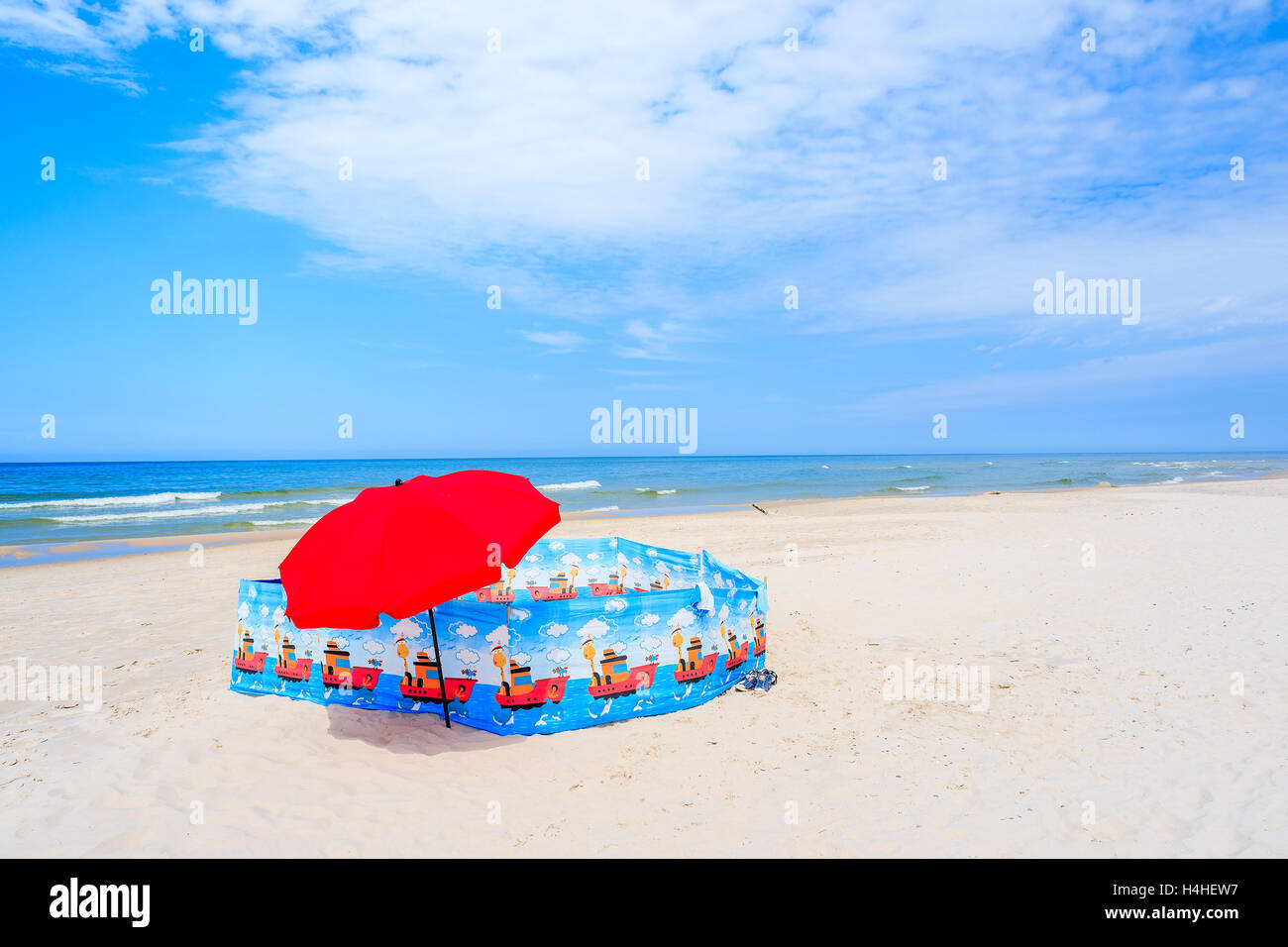 Red umbrella and windbreak on beautiful sandy beach in Leba town, Baltic Sea, Poland Stock Photo
