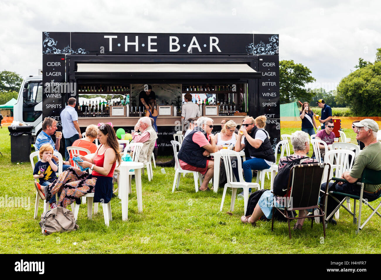 People of all ages drinking beverages from a mobile licensed bar in an open field, at the Royal Cheshire County Show,England. Stock Photo