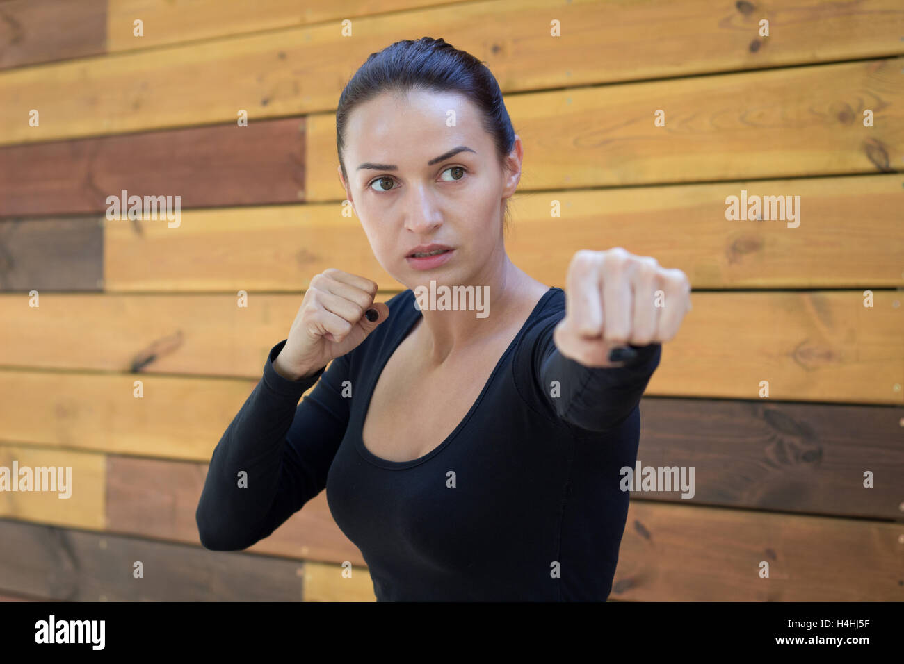 Young pretty fitness woman exercises during boxing training workout at wooden pallete background Stock Photo