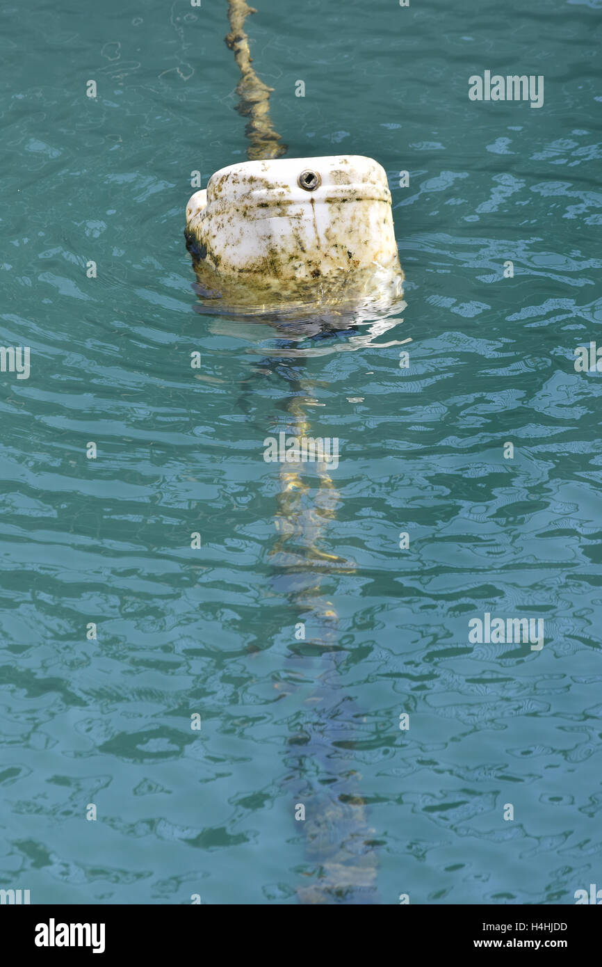 Dirty buoy made of plastic barrel attached to rope floating on green water surface. Stock Photo