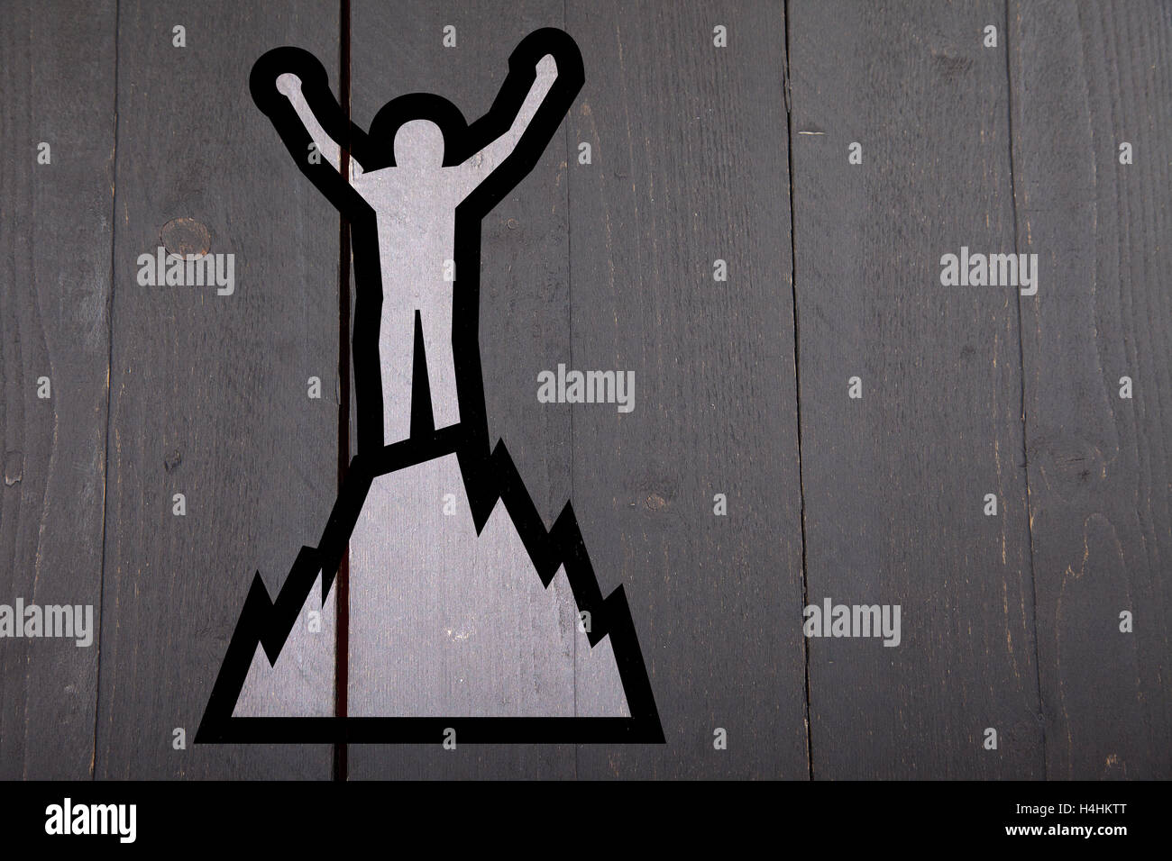 Illustration of man on top of mountain on black wooden background Stock Photo