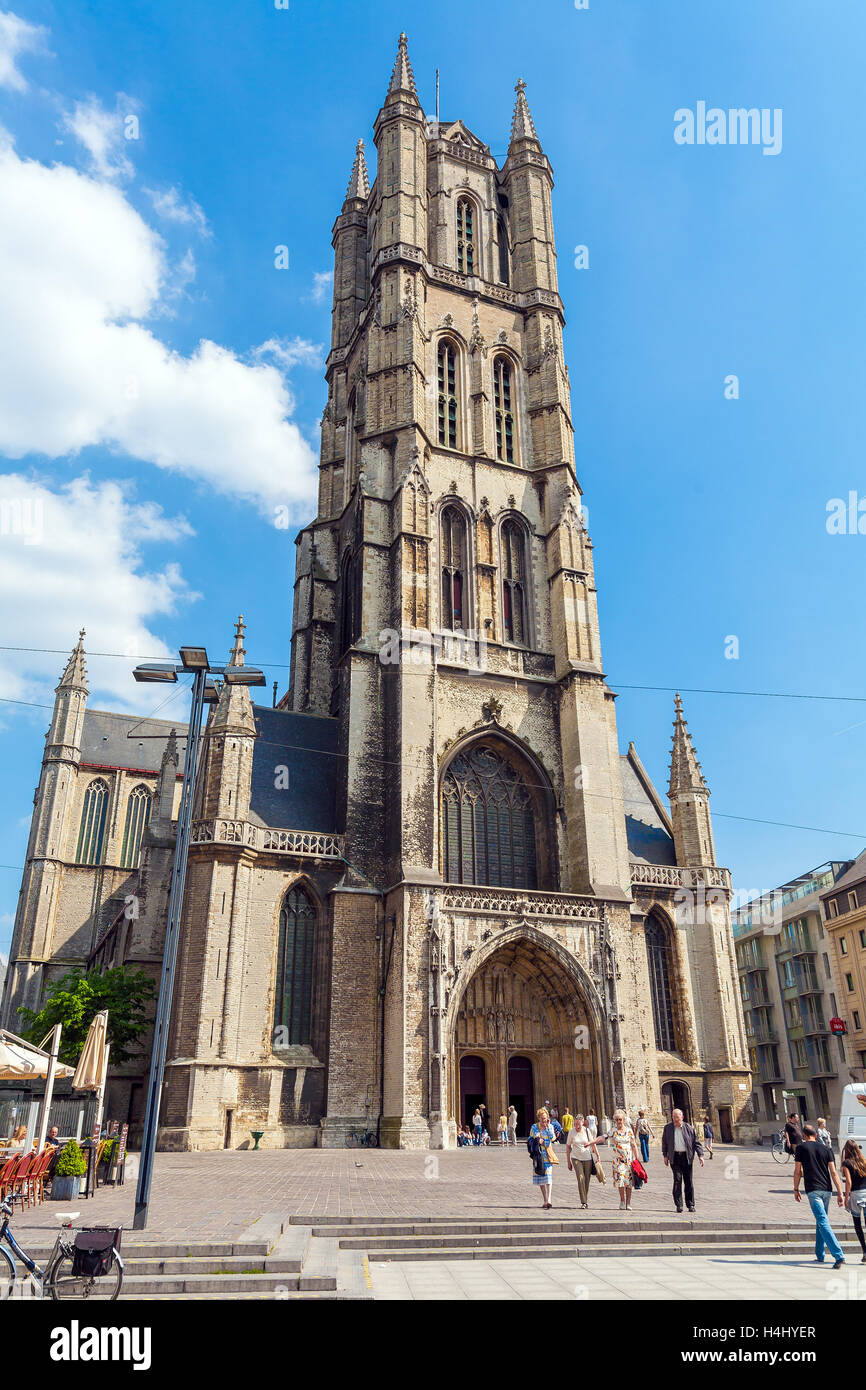 GHENT, BELGIUM - APRIL 6, 2008: Tourists walk on Sint-Baafsplein with Saint Bavo's Cathedral Stock Photo