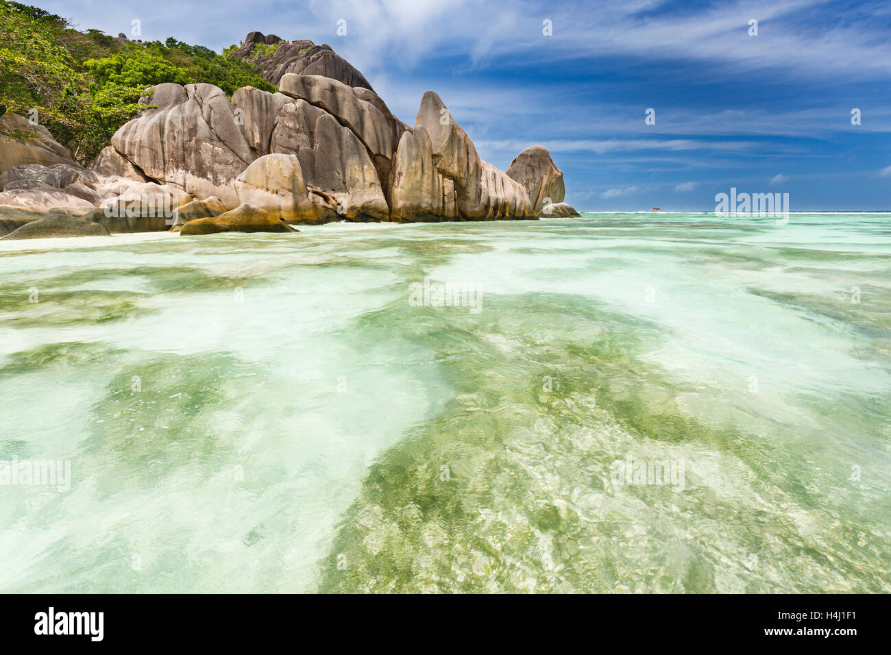 Turquoise water and coral reefs in front of the La Digue coastline, Seychelles with granite rocks Stock Photo