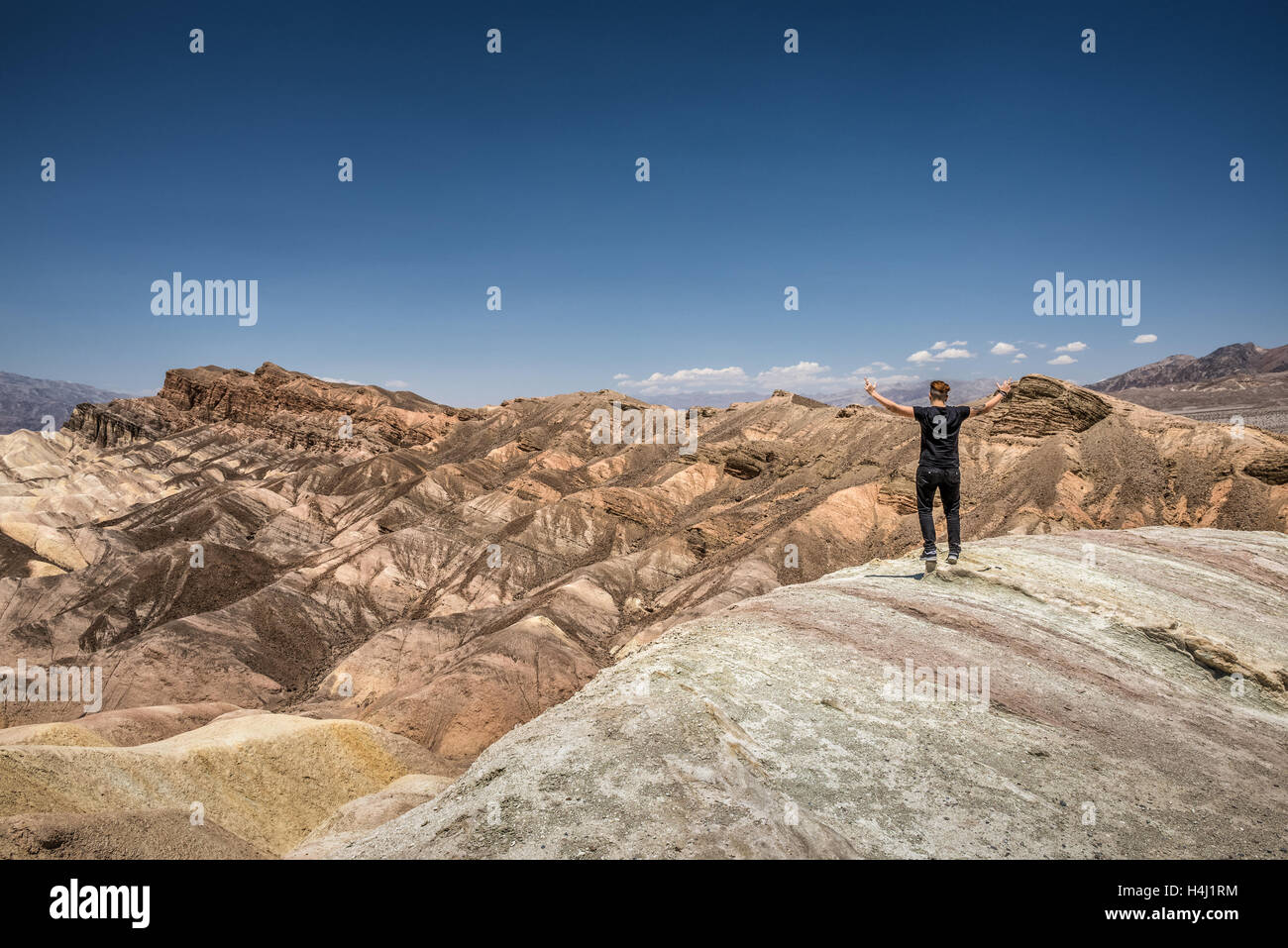 Death Valley and a happy hiker standing on the rim with arms raised up. Winner, success and achievement  concept in nature. Stock Photo