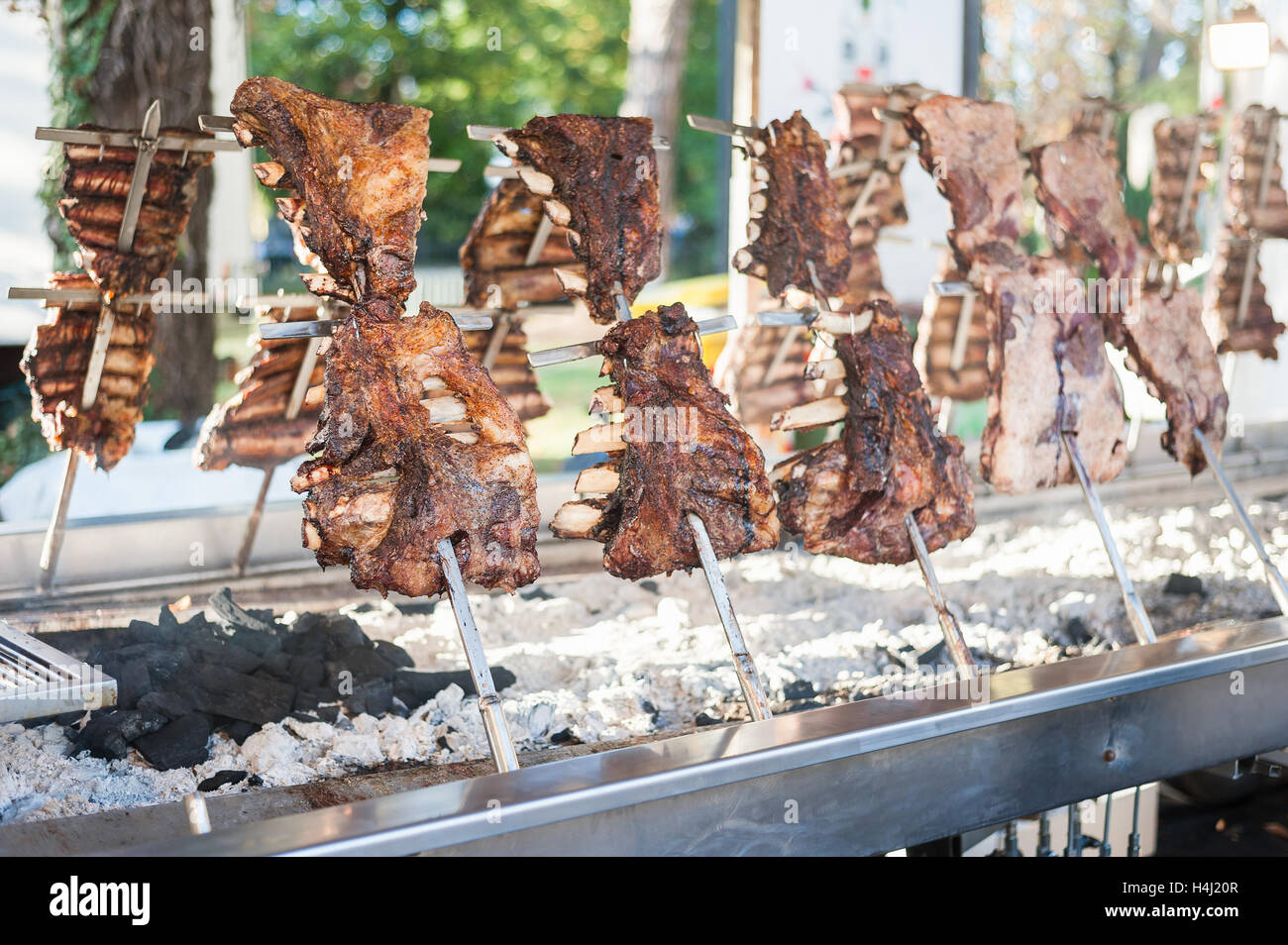 Asado, traditional barbecue dish in Argentina, roasted meat of beef cooked on a vertical grills placed around fire Stock Photo