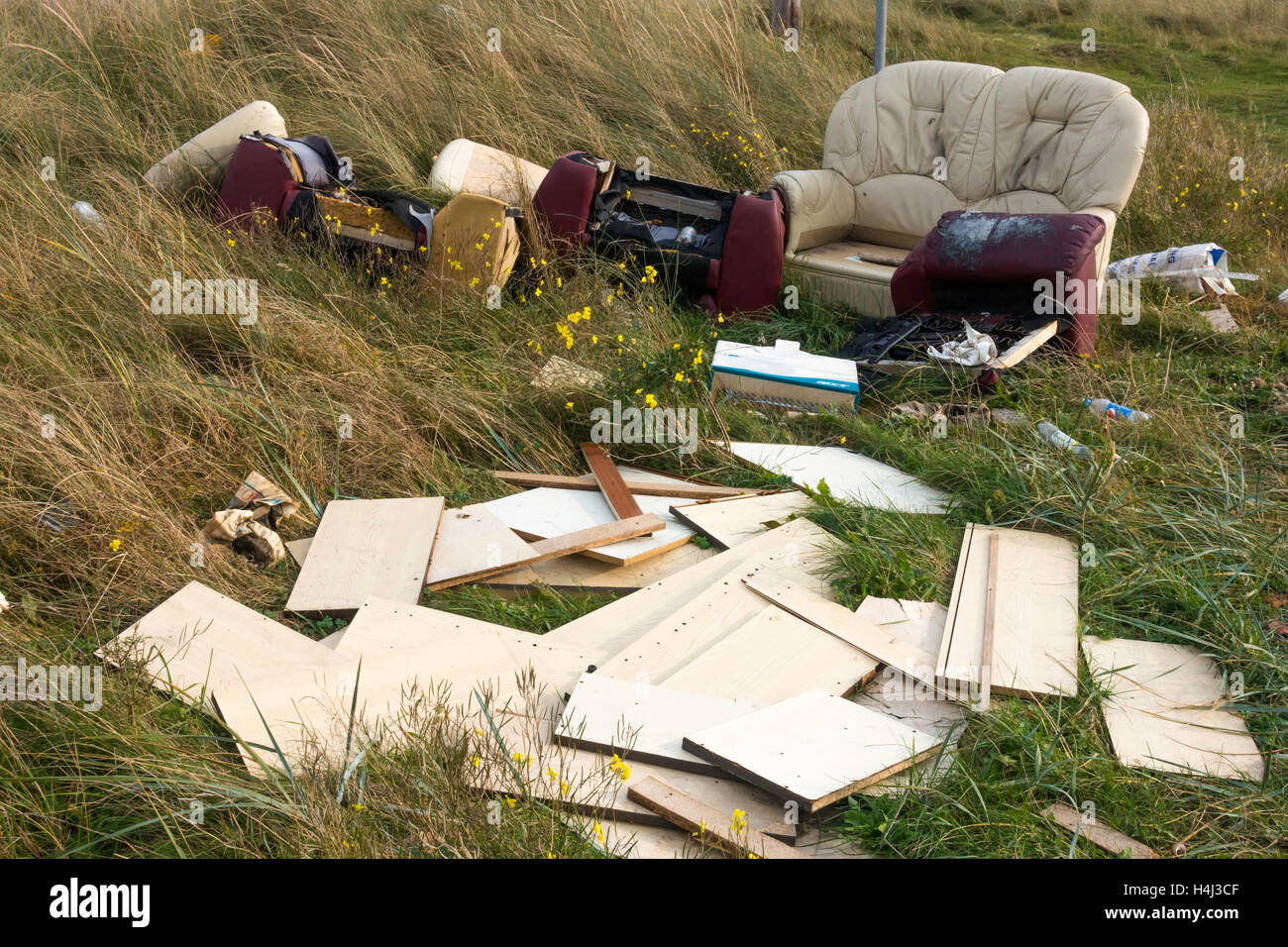 Fly tipping old furniture and other household rubbish illegally dumped by the road side Stock Photo