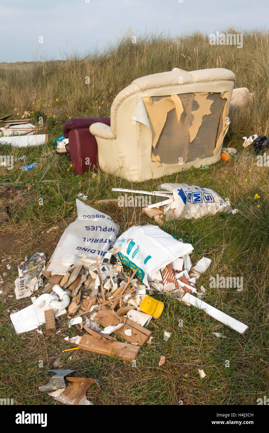 Fly tipping old furniture and other household rubbish illegally dumped by the road side Stock Photo