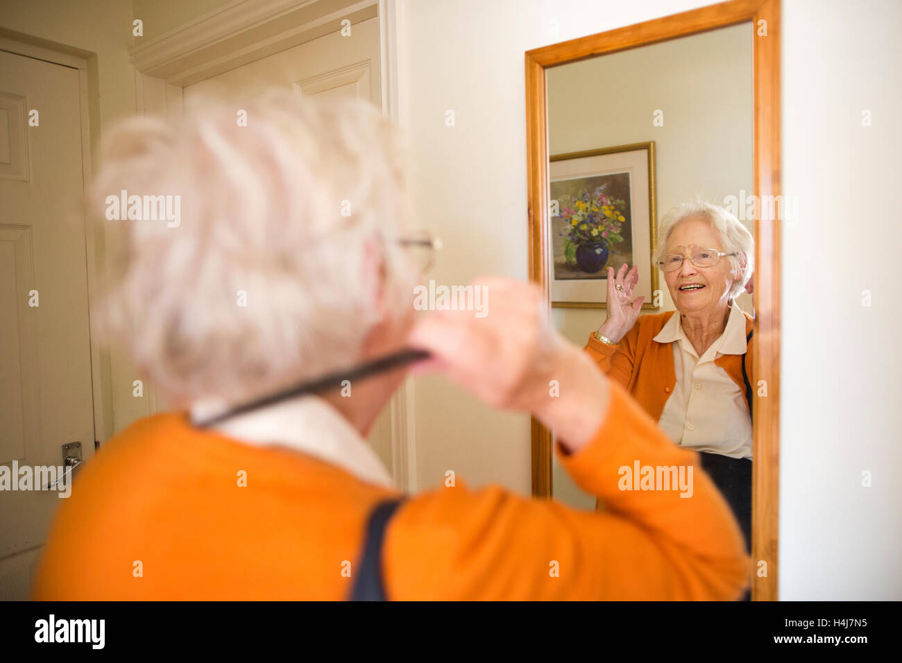 Elderly lady combing her hair in mirror at home, UK Stock Photo