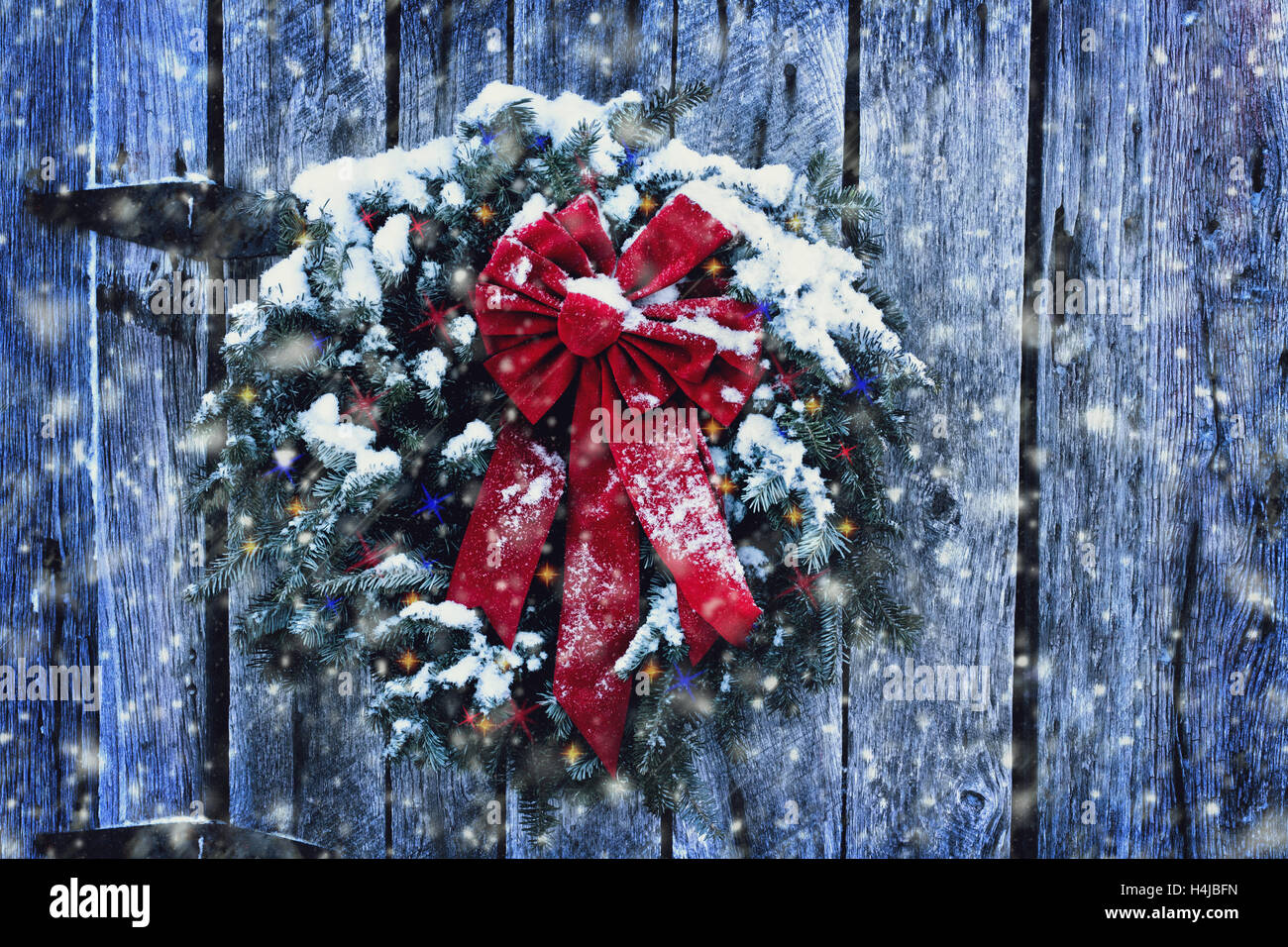 Rustic Christmas wreath on old weathered door with Christmas lights in
