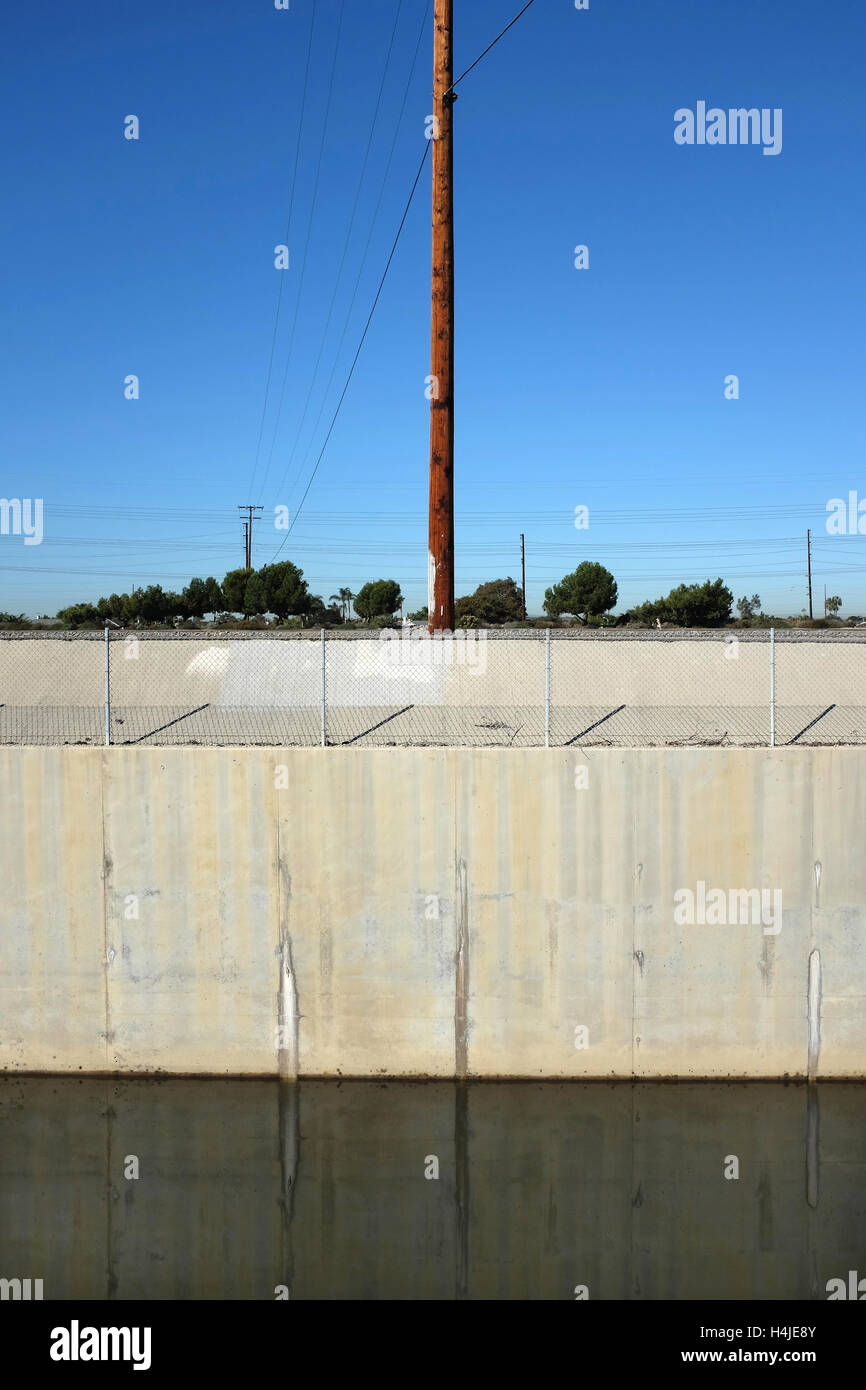 Greenville-Banning flood control channel and power poles in vertical format. The cannnel runs adjacent to the Santa Ana River in Stock Photo
