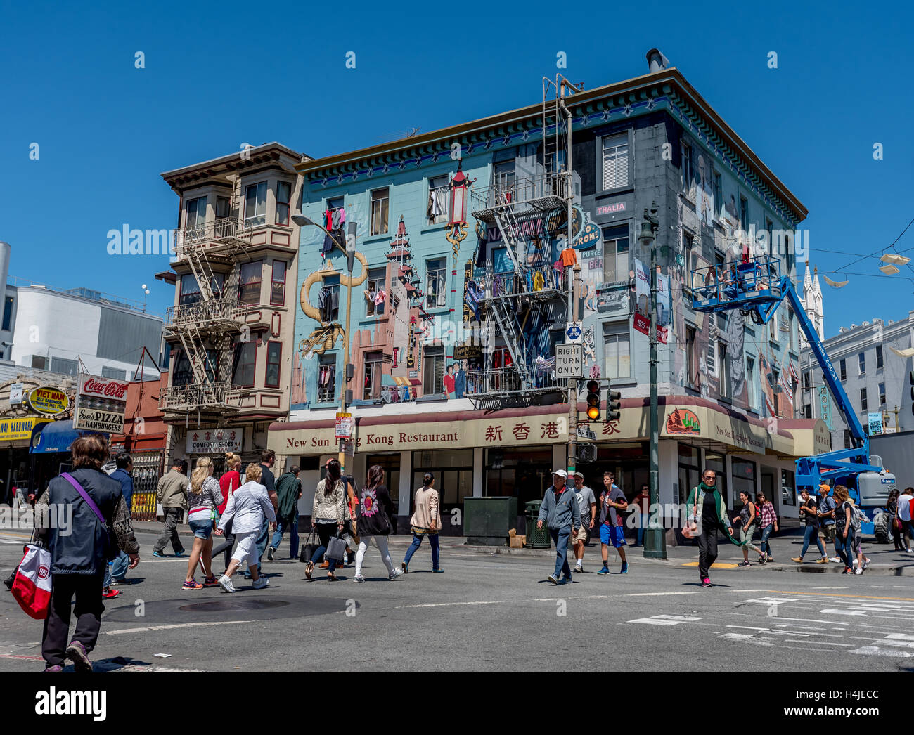 Busy street scene: Artists touch up murals on apartment building above New Sun Hong Kong Restaurant in San Francisco Chinatown. Stock Photo