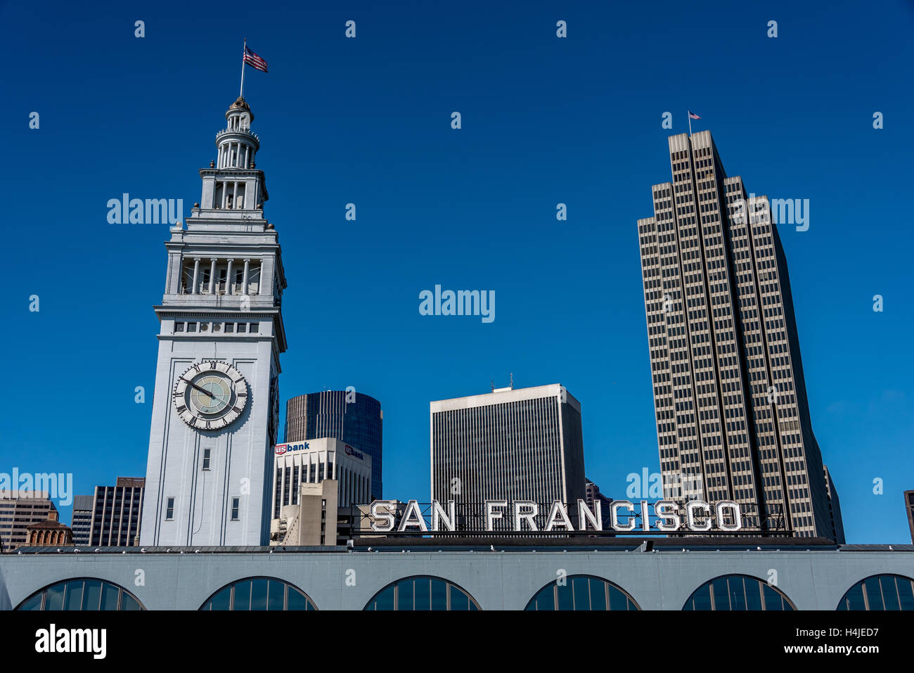 Arriving by ferry at San Francisco ferry building terminal with clock tower, Embarcadero, San Francisco sign, blue sky, flag. Stock Photo