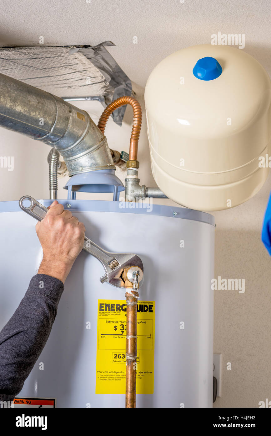Handyman tightens fitting on a hot water heater Stock Photo