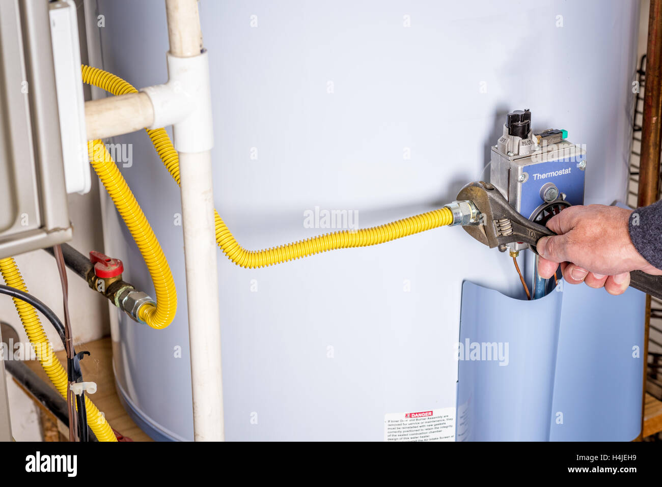 Handyman attaches a gas line to a water heater Stock Photo